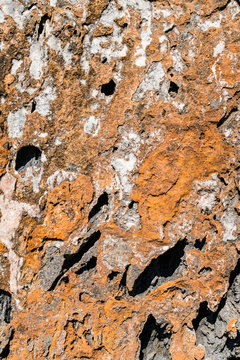 Texture on rocks with orange tones and holes in rocky clifss close to sea in Asturian Coast, Spain