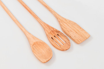 Detail photo of three kitchen spoons made of precious wood on a white background.