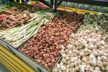 Vegetables on shelves in supermarket with fresh chilli, dry onion, dry ginger, dry citronella...