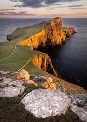 Neist Point, famous landmark with lighthouse on Isle of Skye, Scotland lit by setting sun.