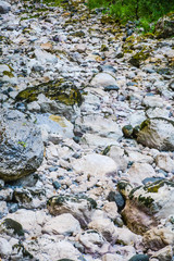 Large boulders and small stones cover a dry river bed at the bottom of the gorge