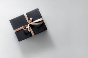 Gift wrapped in dark paper on pastel background