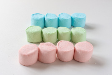 Rows of colored marshmallows on a white table. Marshmallow figures.