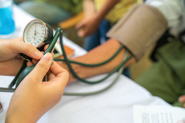 Volunteer nurse measuring blood pressure of poor Asian people outdoors closeup