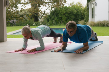 Fototapeta na wymiar Active senior couple doing plank exercise in the porch at home