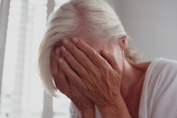 Active senior woman covering face with her hands at home