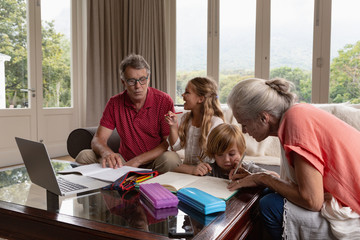 Grandparents helping grandchildren with homework in living room