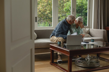 Active senior couple calculating bills in living room