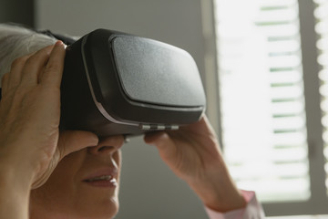 Active senior woman using virtual reality headset in living room