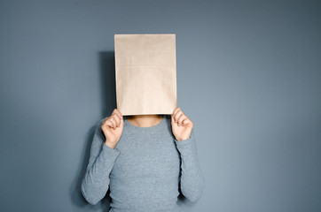 Girl with paper bag on her head on grey background