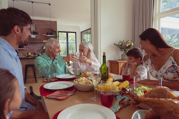Multi-generation family toasting glasses of champagne on dining table at home