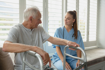 Fototapeta premium Female doctor interacting with active senior man on window seat