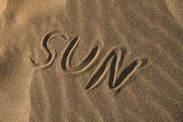 Fototapeta na wymiar sun written on the sand