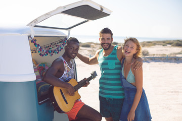 Group of friends having fun together near camper van at beach