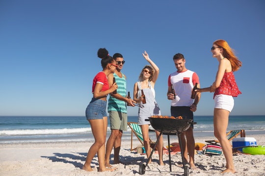 Group of friends having fun while preparing food on barbecue at beach