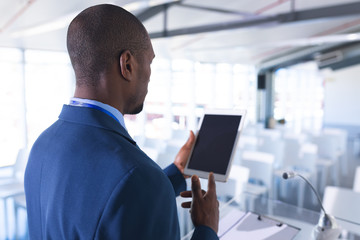 Male speaker practicing his speech on digital tablet in business seminar