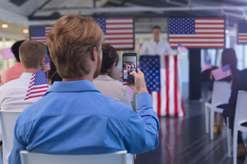 Businessman clicking photo of business seminar with mobile phone