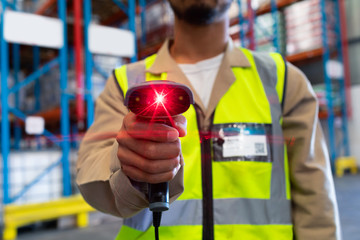 Male worker showing barcode scanner on camera in warehouse