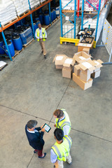 Warehouse staff discussing over digital tablet in warehouse