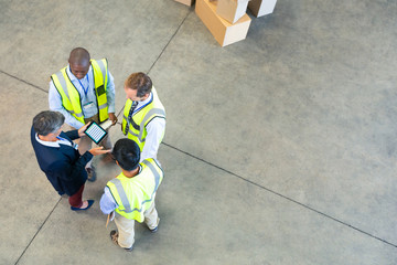 Warehouse staff discussing over digital tablet in warehouse
