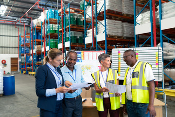 Staffs discussing over document in warehouse