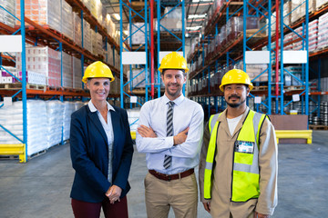 Happy staffs looking at camera in warehouse