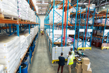 Warehouse staff discussing over whiteboard in warehouse