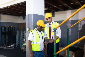 Male supervisor with his coworker discussing over digital tablet