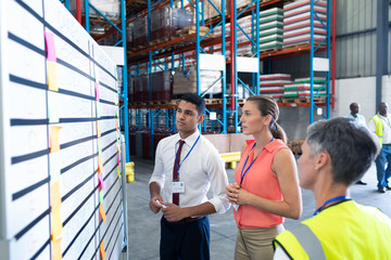 Warehouse staffs looking at whiteboard in warehouse