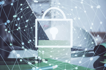 Double exposure of desktop with computer and lock icon hologram. Concept of data safety.
