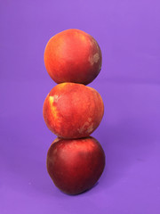 three red peaches on a purple background