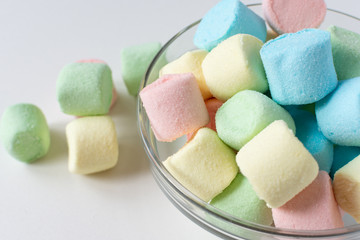 Colored marshmallows in a plate on a white background. A plate full of sweets.