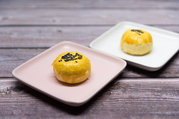Close-up of delicate Asian yellow pastry cuisine laid out on a retro wood dining table
