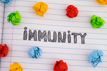The word Immunity on notebook sheet with some colorful crumpled paper balls around it