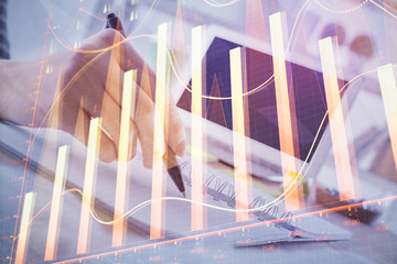 Financial forex graph drawn over hands taking notes background. Concept of research. Multi exposure