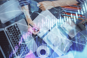 Financial forex graph drawn over hands taking notes background. Concept of research. Double exposure