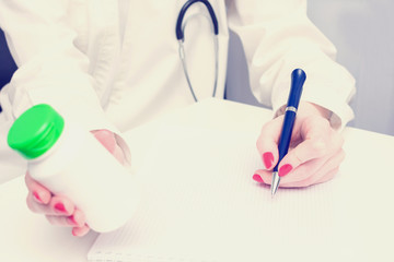 Toned image, doctor wrote a prescription, holds in hand a medicine, copy space