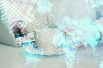 Double exposure of businessman working on laptop on background. International business hologram in front. Concept of success.