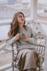 Woman drinking coffee or tea.Young girl with cup of coffee sitting on balcony with city view in morning.