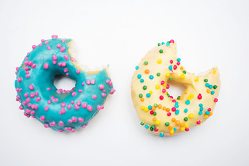 Blue and yellow donuts, two bitten donuts with bright sprinkles, isolated