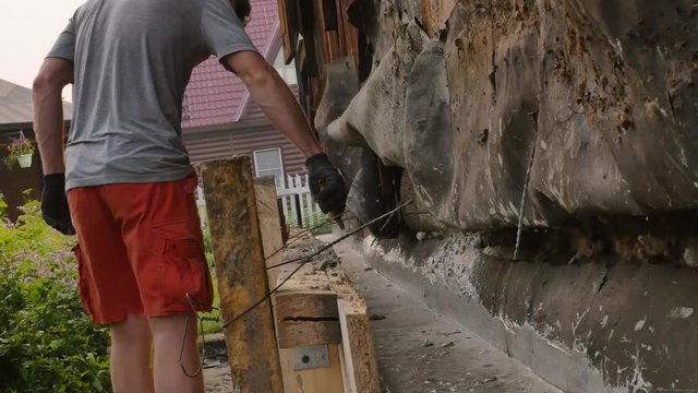 worker dismantles the wooden formwork, new foundation for old house. 4K