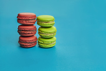 Colored macaron or macaroon, sweet meringue-based confection on blue background. Close-up, copy space.