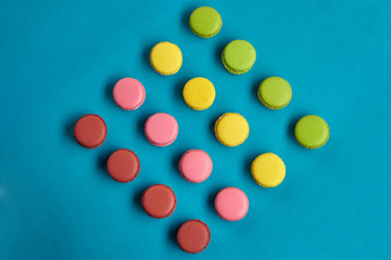 Colored macaron or macaroon, sweet meringue-based confection on blue background. Close-up, copy space.