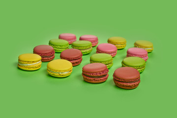 Colored macaron or macaroon, sweet meringue-based confection on green background. Close-up, copy space.