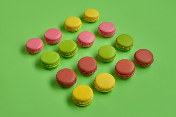 Colored macaron or macaroon, sweet meringue-based confection on green background. Close-up, copy space.