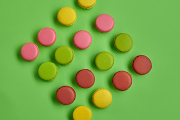 Colored macaron or macaroon, sweet meringue-based confection on green background. Close-up, copy space.