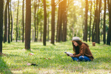 A beautiful Asian woman reading a book while sitting in the park