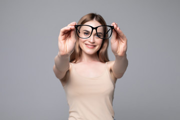 Glasses - optician showing eyewear. Closeup of glasses, with glasses and frame in focus. Woman on gray background.
