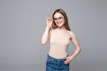 Smiling young woman with eyeglasses over gray background