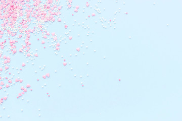 Festive romantic gentle abstract background for the design. Pink confetti in the shape of hearts on a blue background. Top view, flat lay composition. Copy space for text.